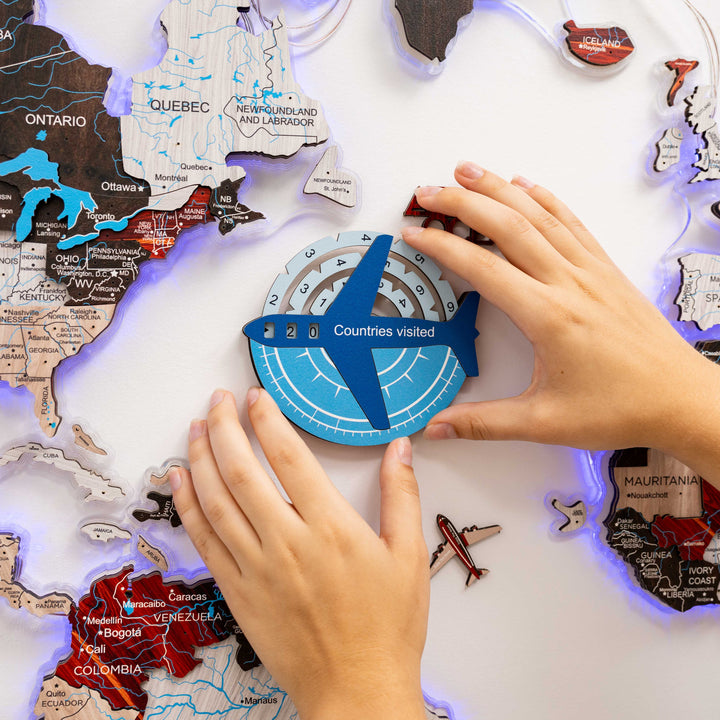 Wooden wall map travel tracker with blue compass; hands adjusting the marker