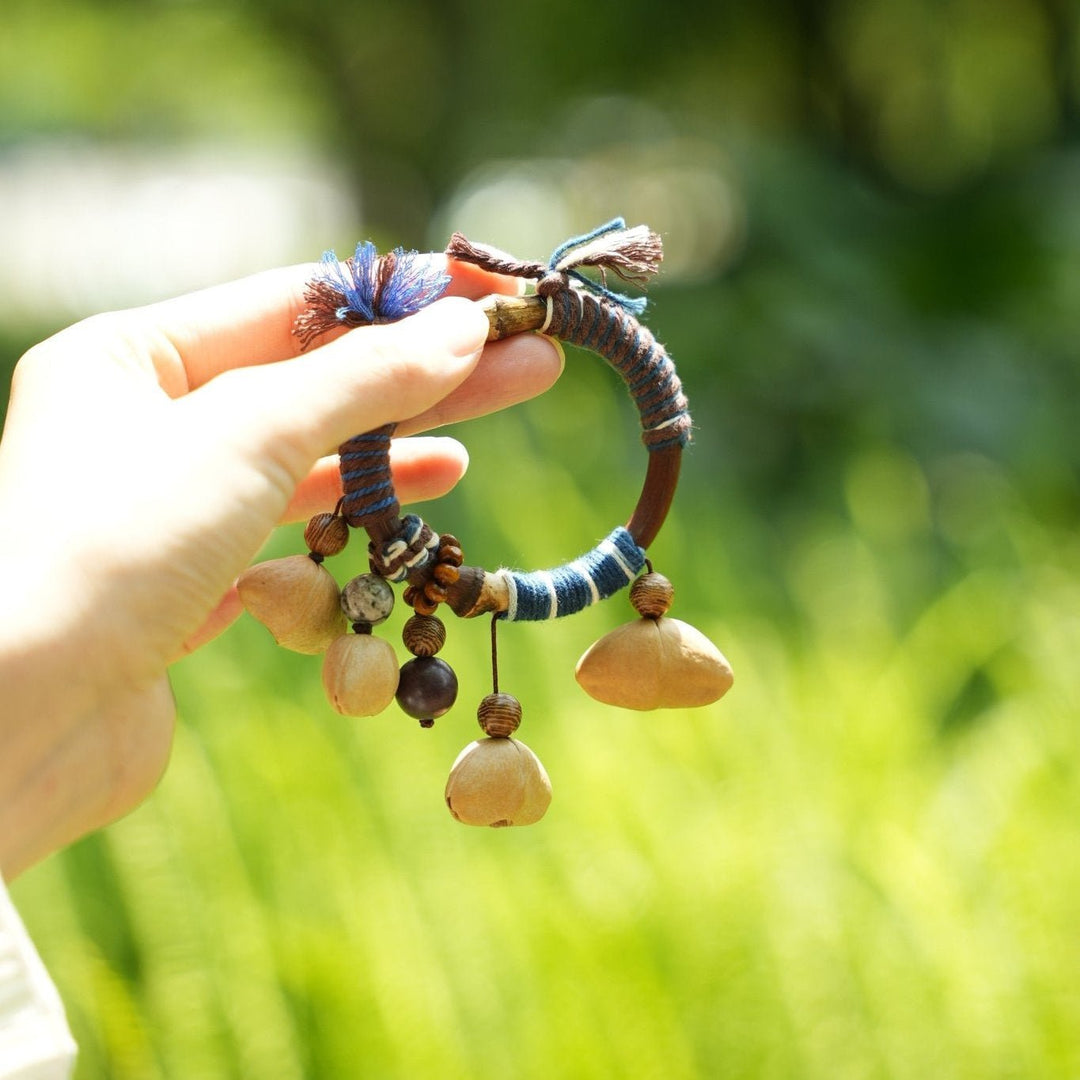 Seed bangle bracelet with braided green band and dangling tan seed pods