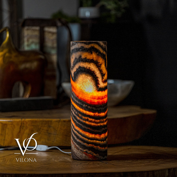 Table lamp with cylindrical onyx-look shade, black, amber, and orange striped glow