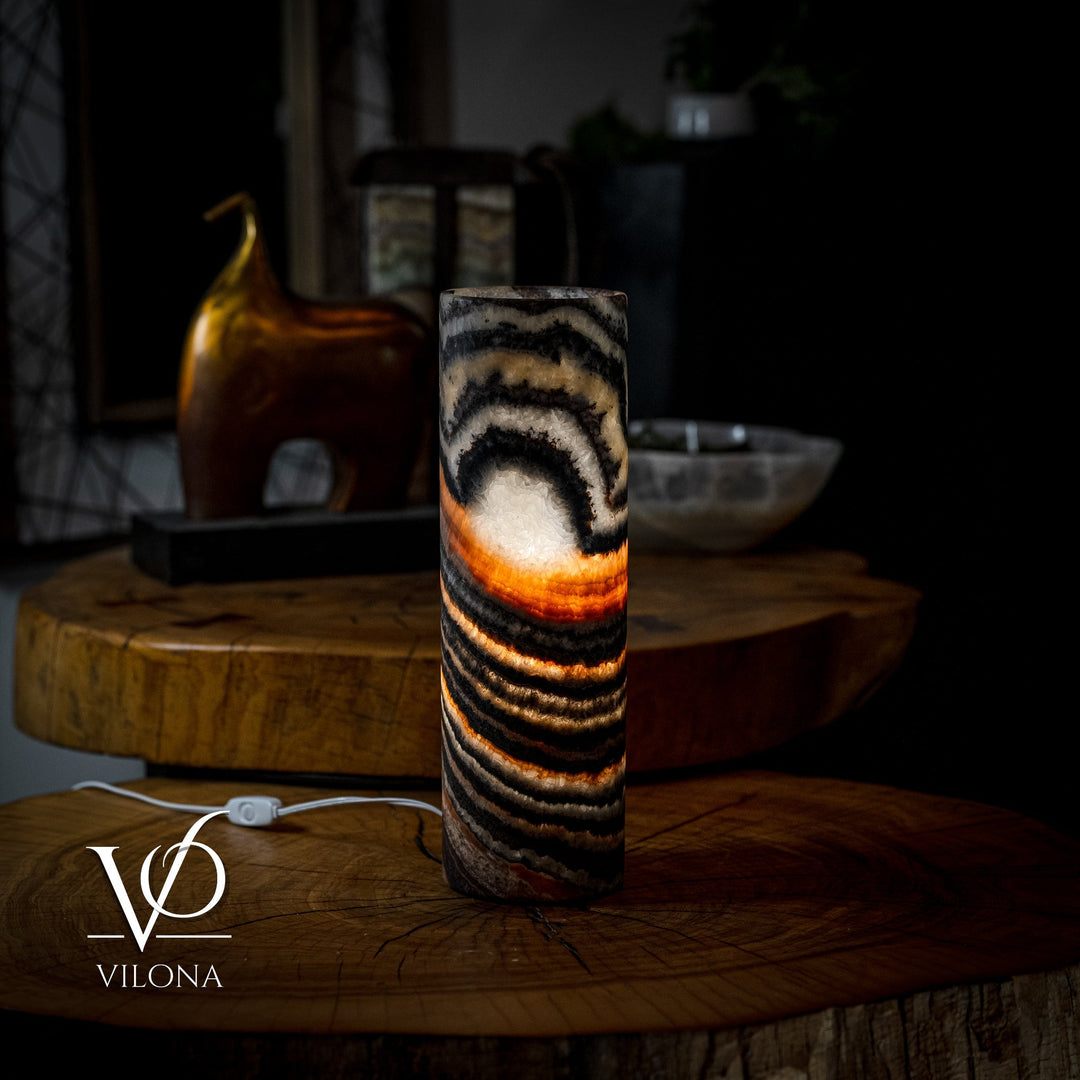 Onyx-look cylindrical table lamp on wood surface with black and amber striped glow