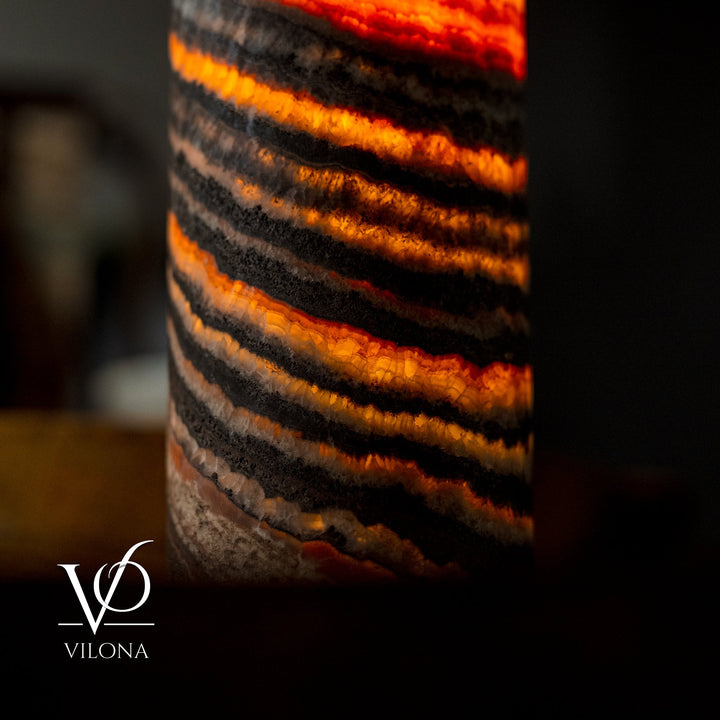 Detail of striped cylindrical onyx-look lamp shade in black with orange and amber bands