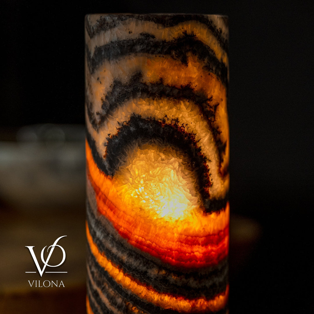 Table lamp showing warm amber light through black and orange striped cylindrical shade