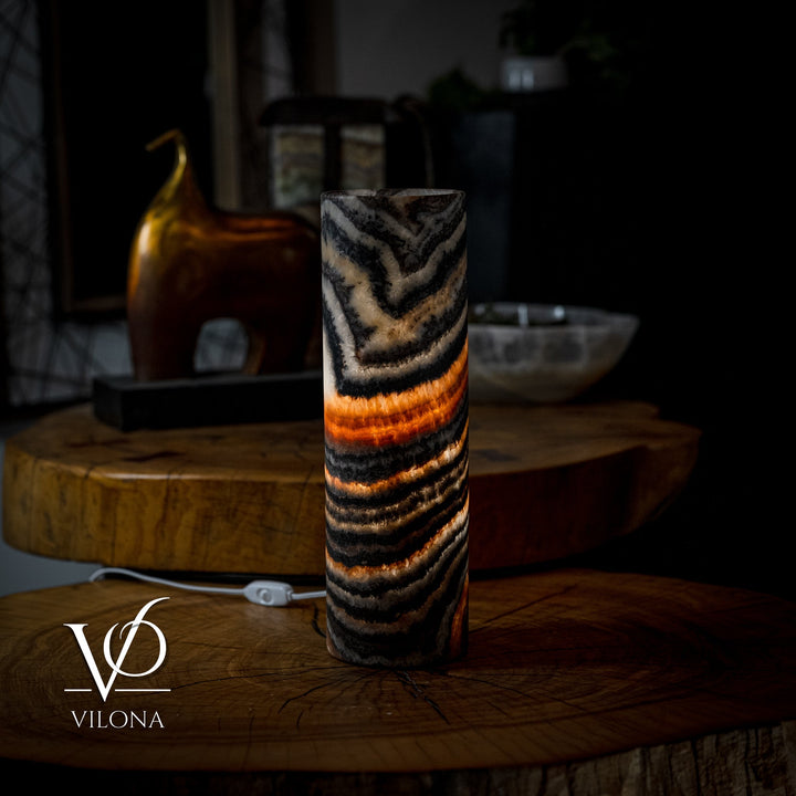 Cylindrical onyx-look table lamp with wavy black and tan stripes and warm orange glow
