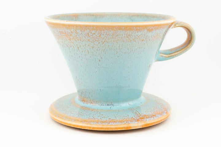 V60 ceramic coffee dripper with drip stand, speckled light blue glaze and side handle.