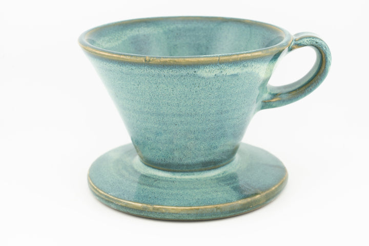 V60 ceramic coffee dripper with integrated drip stand, teal glaze and side handle.