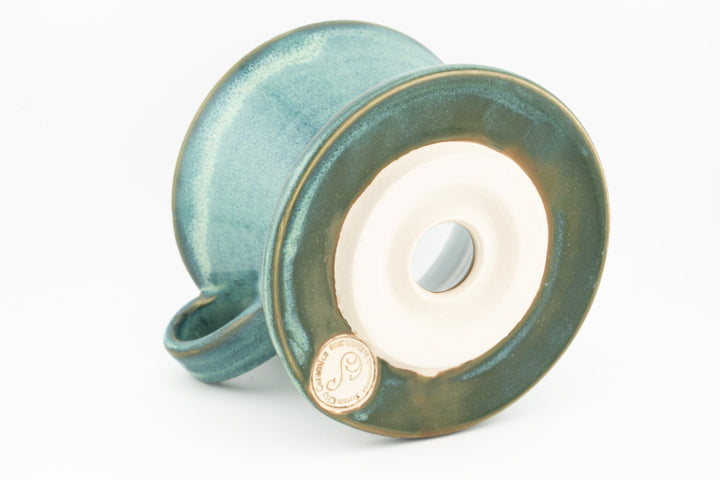 V60 ceramic coffee dripper underside with circular vent and teal glaze, side handle.