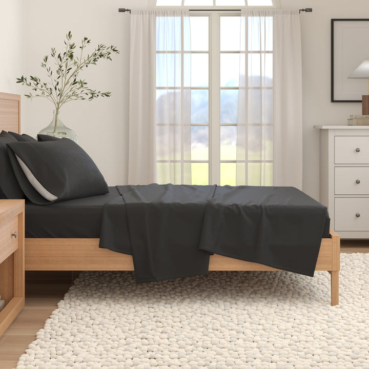 Cotton solid flannel sheet set in dark charcoal draped on a bed
