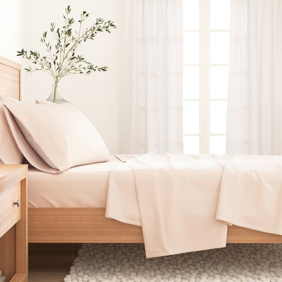 Blush pink cotton flannel sheet set draped on bed with pillowcase