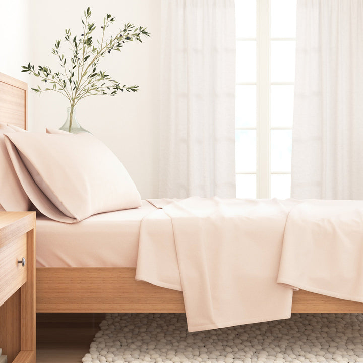 Blush pink cotton flannel sheet set draped on bed with pillowcase