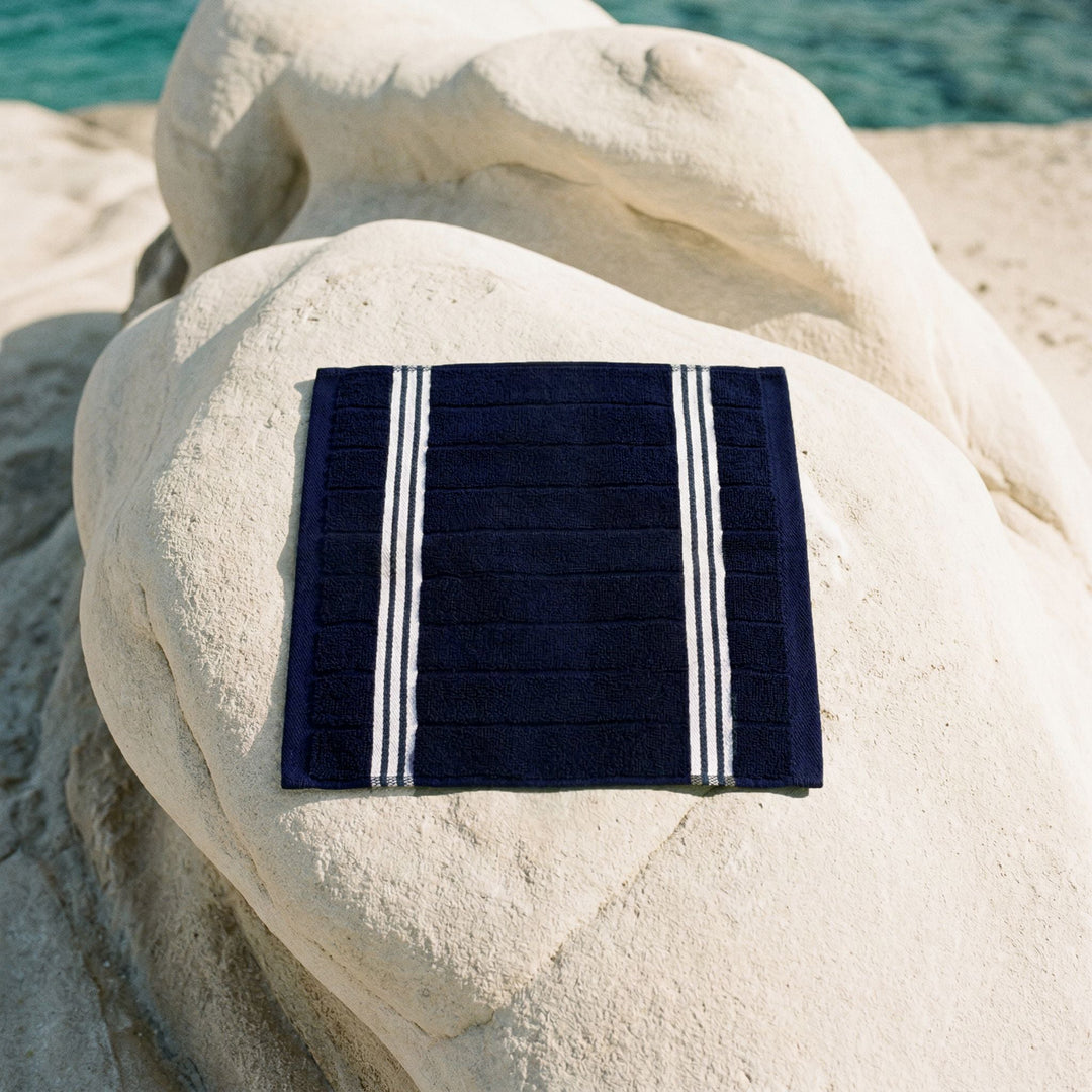 Navy cotton towel with white striped border, folded square