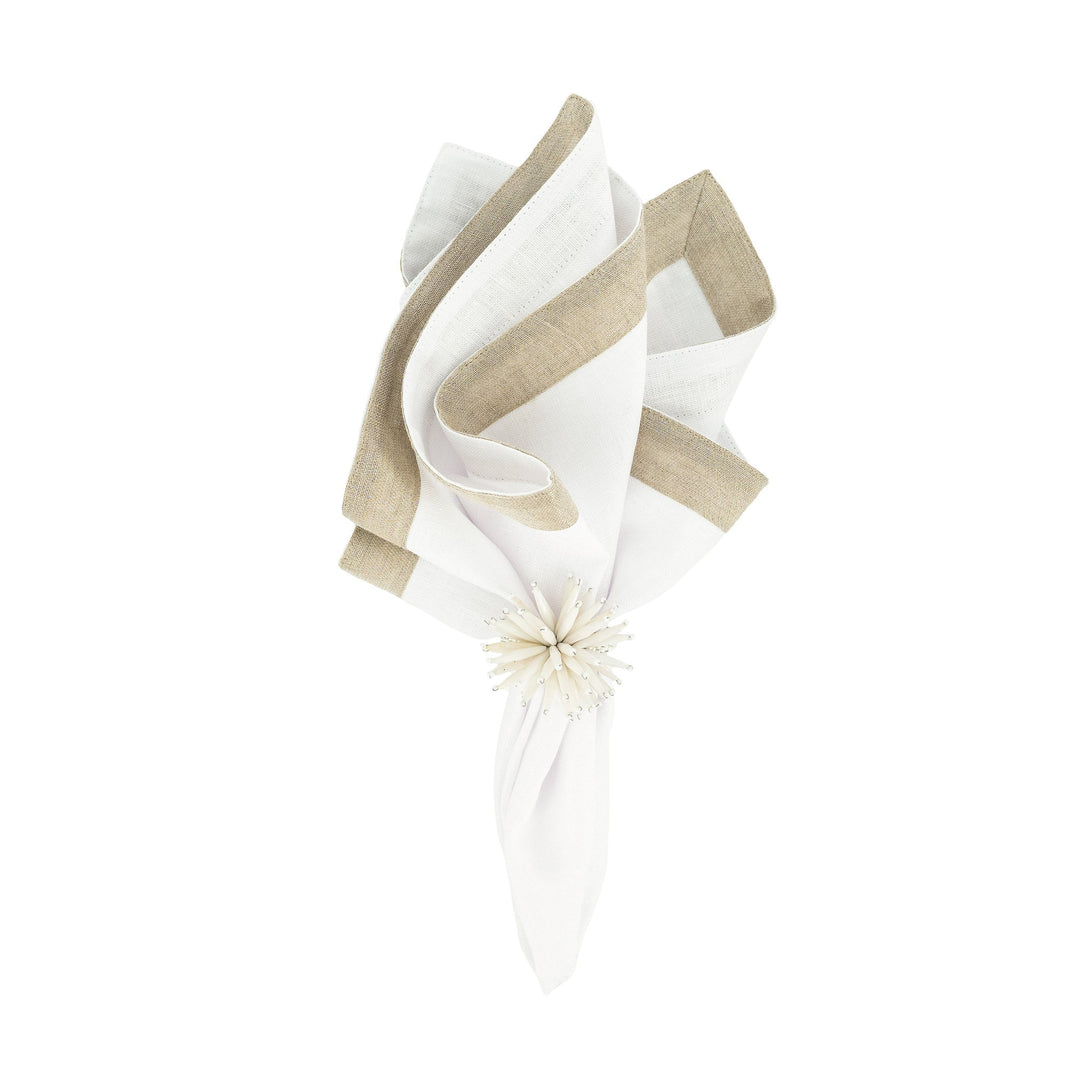 Folded linen napkin with white fabric and tan sparkle border, tied with a small white flower.