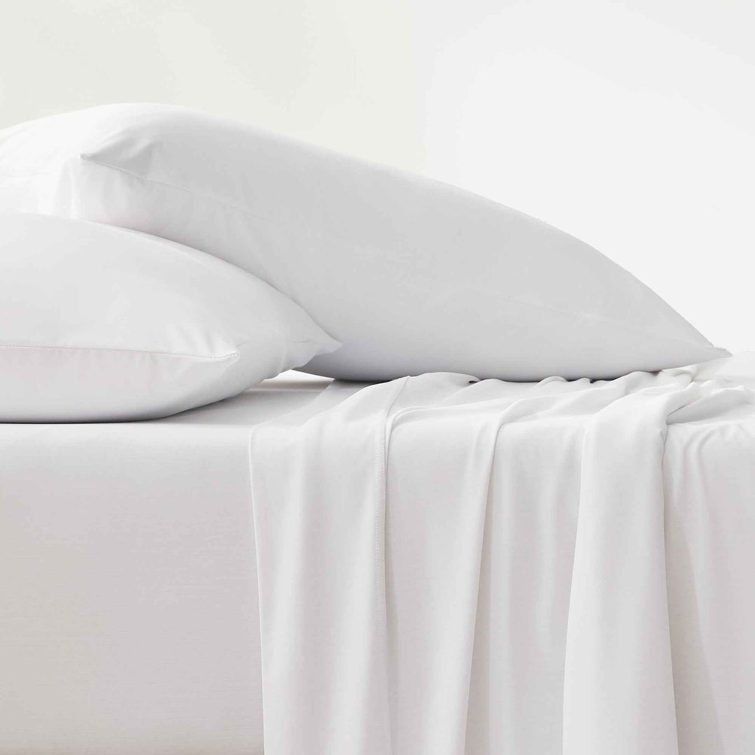 White cooling sheets with pillowcases and draped top sheet detail