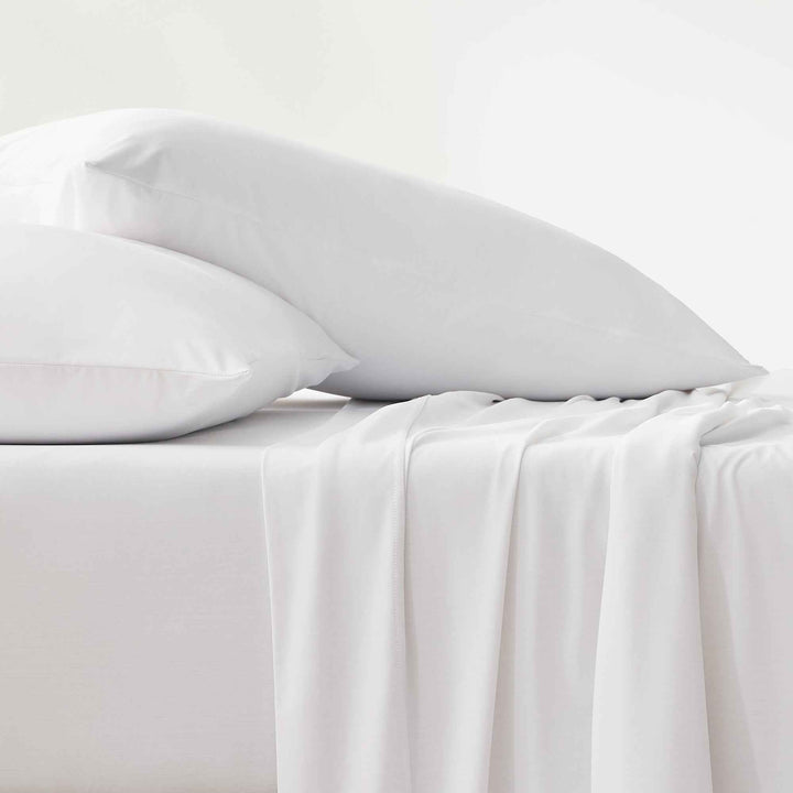 White cooling sheets with pillowcases and draped top sheet detail