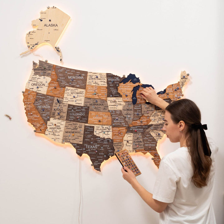 Wooden 3D LED USA map with multicolor states and warm backlighting as a hand points