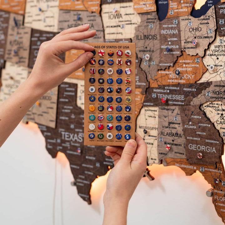Hands holding a sticker sheet over the wooden 3D LED USA map state labels