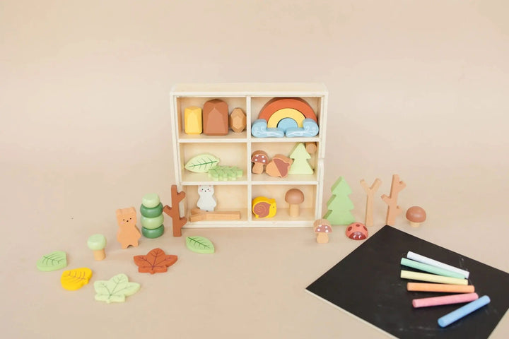 Open wooden forest sensory bin with compartment pieces and chalkboard with crayons