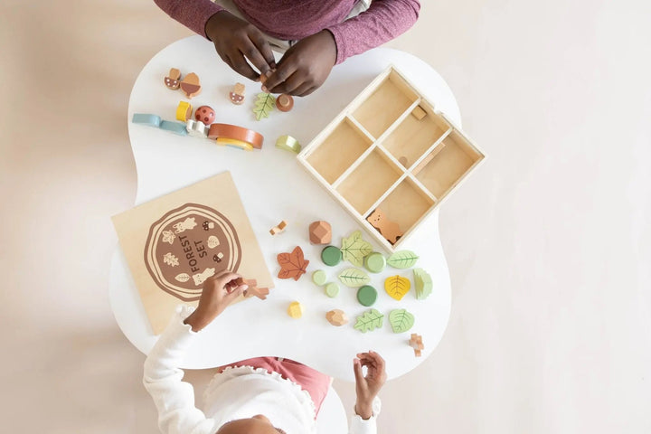 Wooden forest sensory bin with lid and woodland pieces placed on the floor