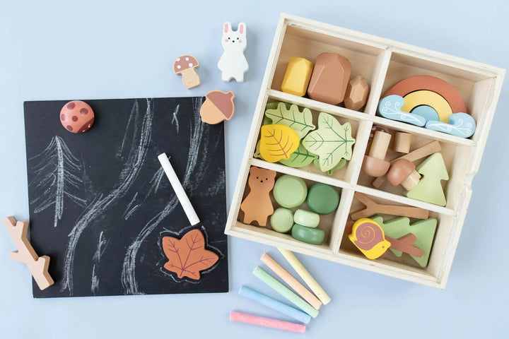 Wooden forest sensory bin open with wooden animals, leaves, and rainbow arch