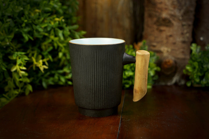 Dark ribbed ceramic mug with mint interior and light wood handle on table