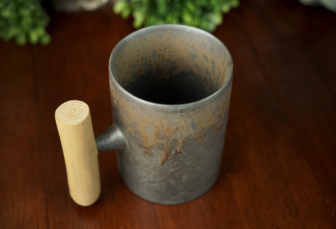Glazed ceramic mug with wooden handle, interior visible, iron bronze glazed finish