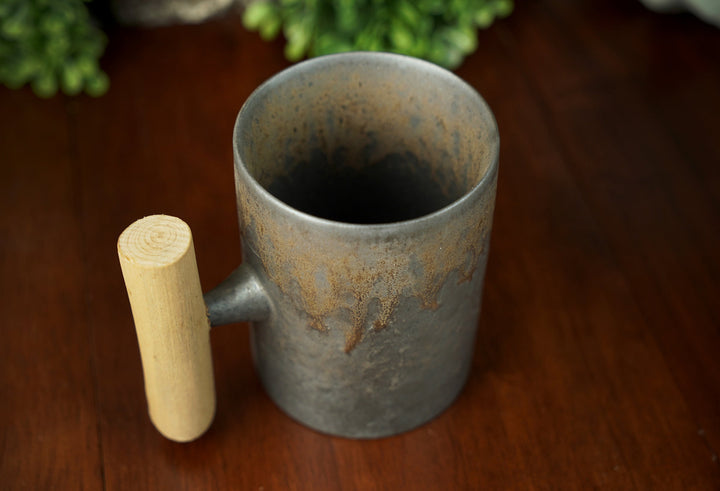 Glazed ceramic mug with wooden handle, interior visible, iron bronze glazed finish
