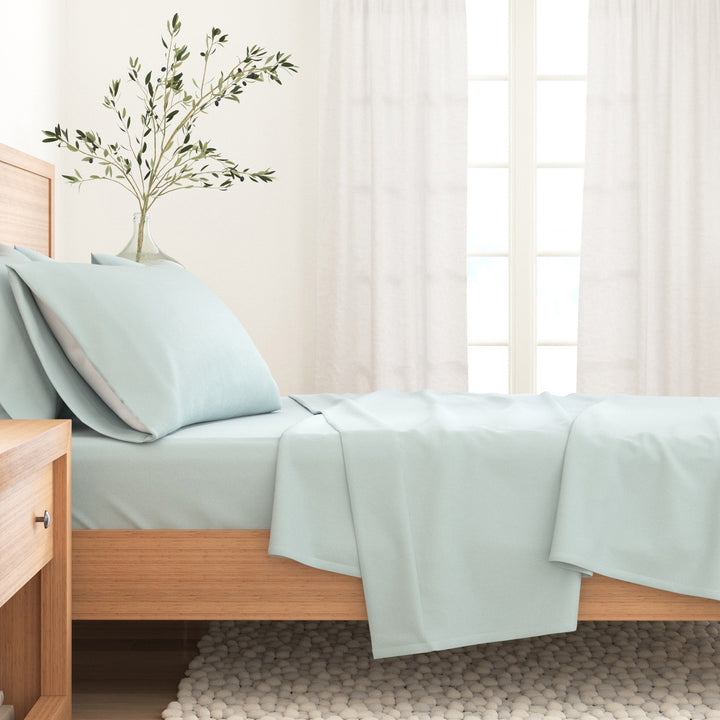 Light blue cotton flannel sheet set neatly folded on a bed