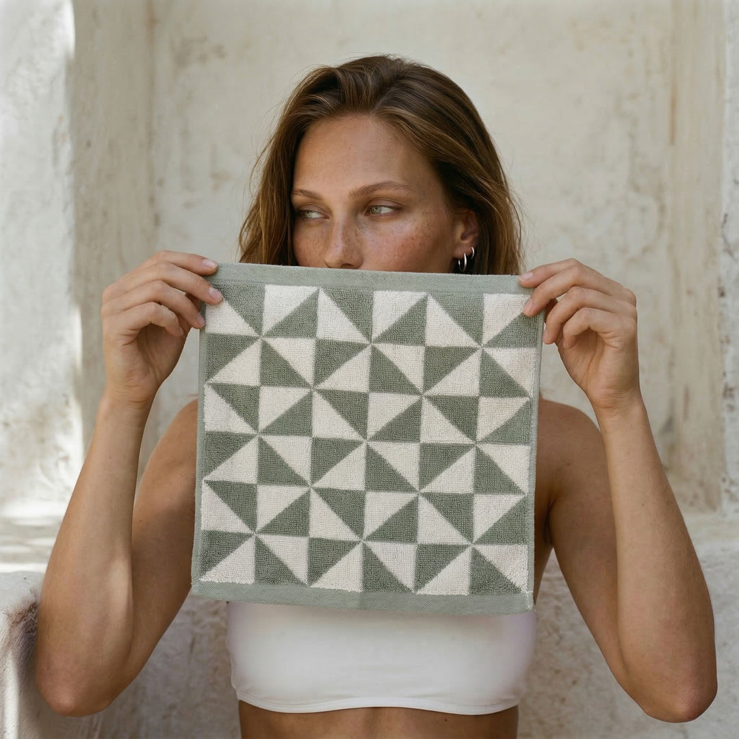 Green and light gray geometric cotton towel held up in front of the model.