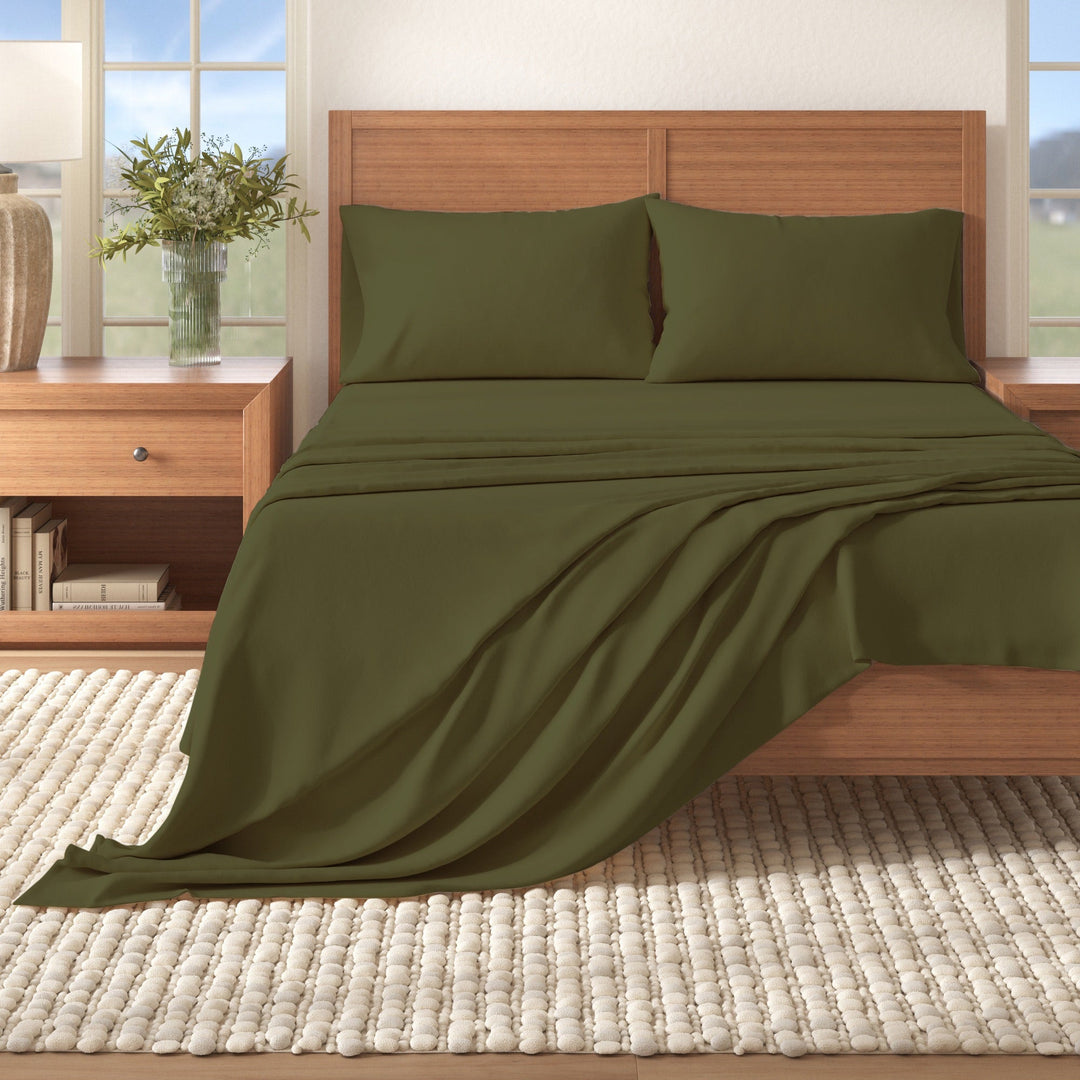 Solid cotton flannel sheet set in olive green on a bed, draped bedding and pillows