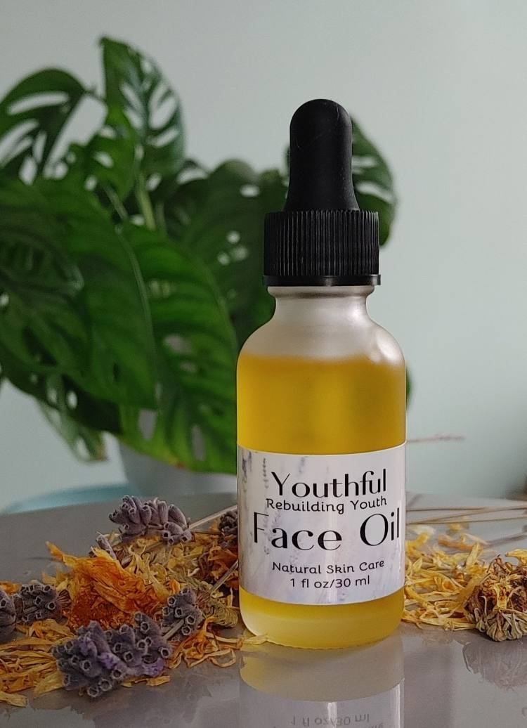 Youthful face oil bottle with dropper; amber yellow liquid, herbal label