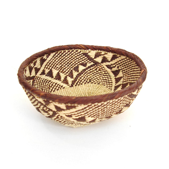 Round woven basket bowl in tan with dark brown repeating triangle and diamond pattern